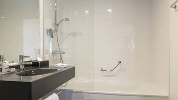 Une salle de bain moderne avec un grand miroir, un lavabo et une baignoire.
