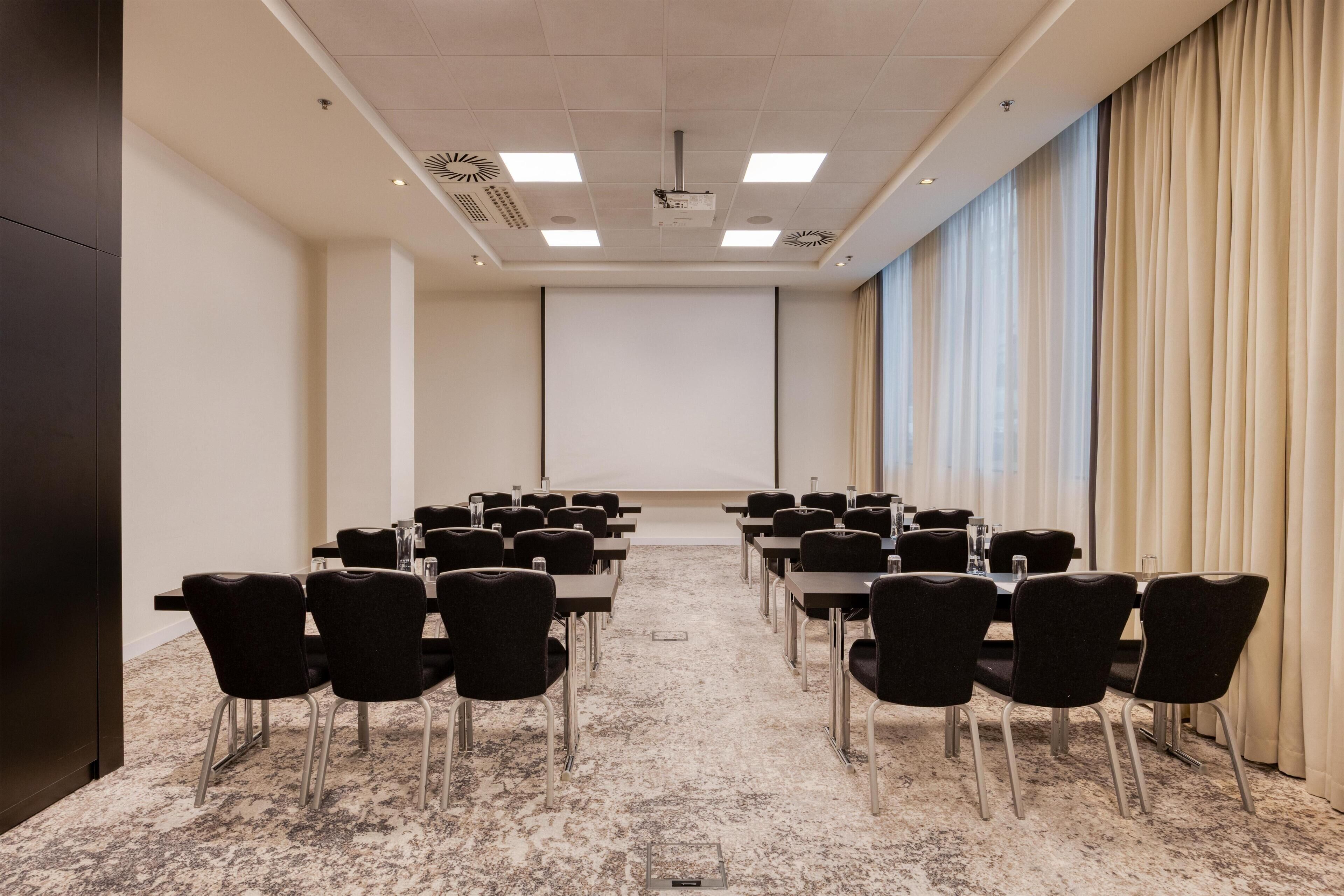 A conference room with a long table, chairs, a projector screen, and a large window with curtains.