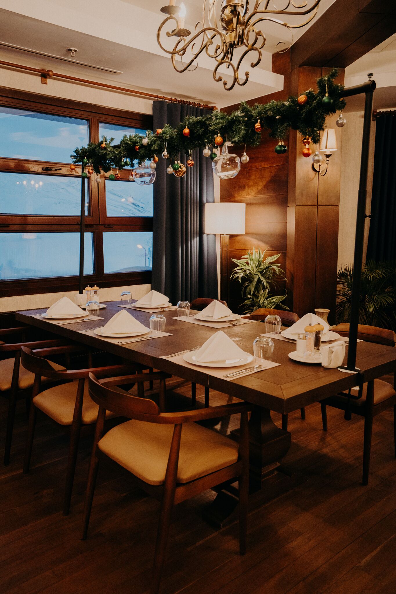 A dining area with a long wooden table set for a meal, surrounded by chairs.