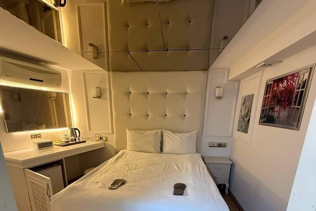 Une chambre à coucher avec un grand lit, une table de chevet, un miroir et une fenêtre donnant sur un beau paysage.