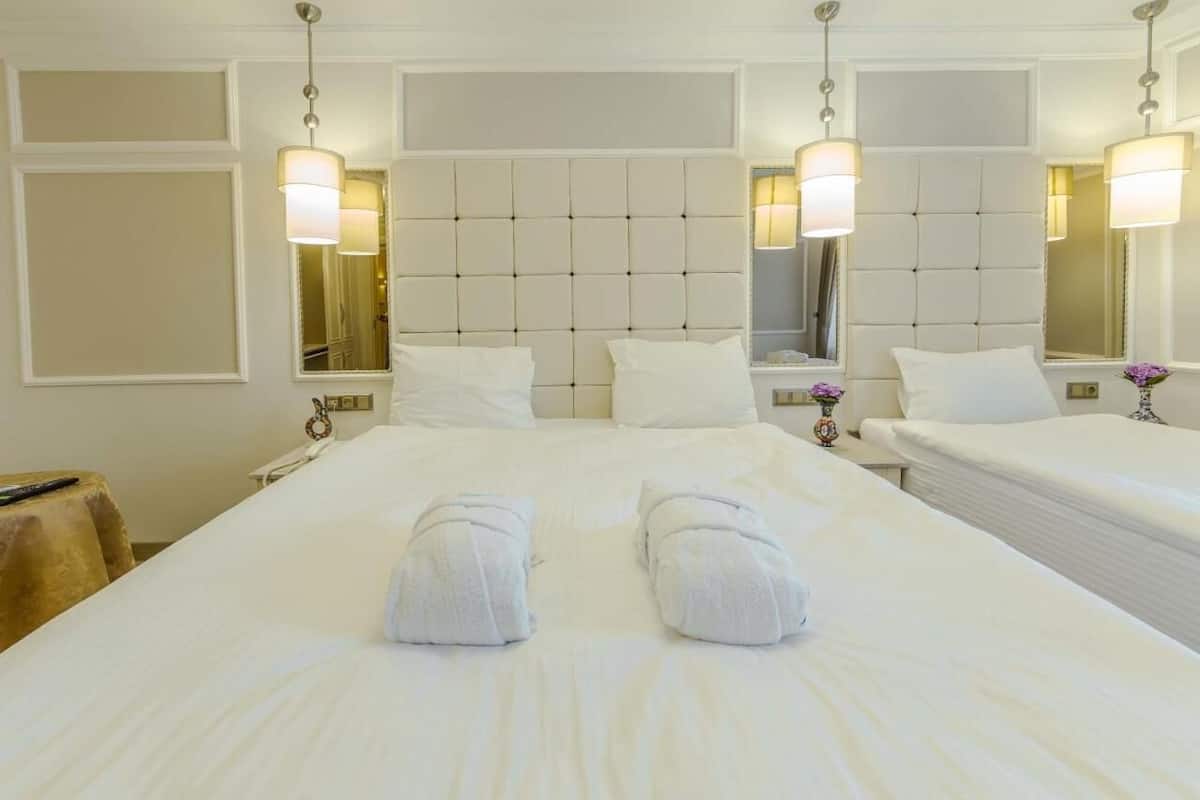 Une chambre d’hôtel avec un grand lit, deux tables de chevet et un miroir au-dessus du lit.