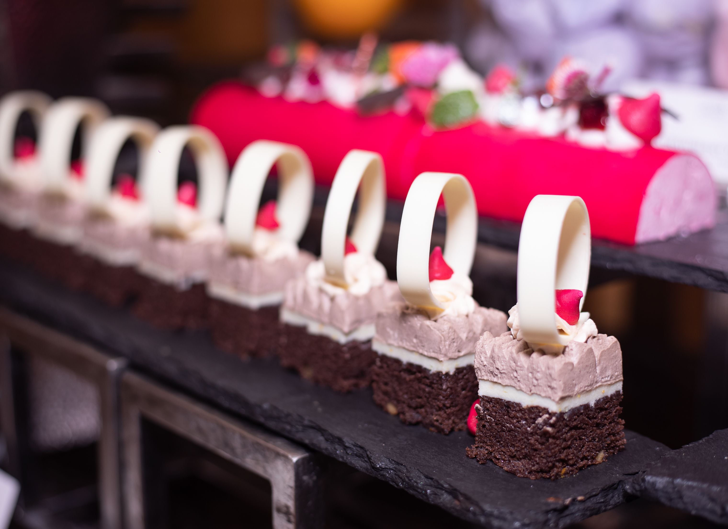 Una exhibición de postres con pasteles de chocolate y decoraciones de chocolate blanco.