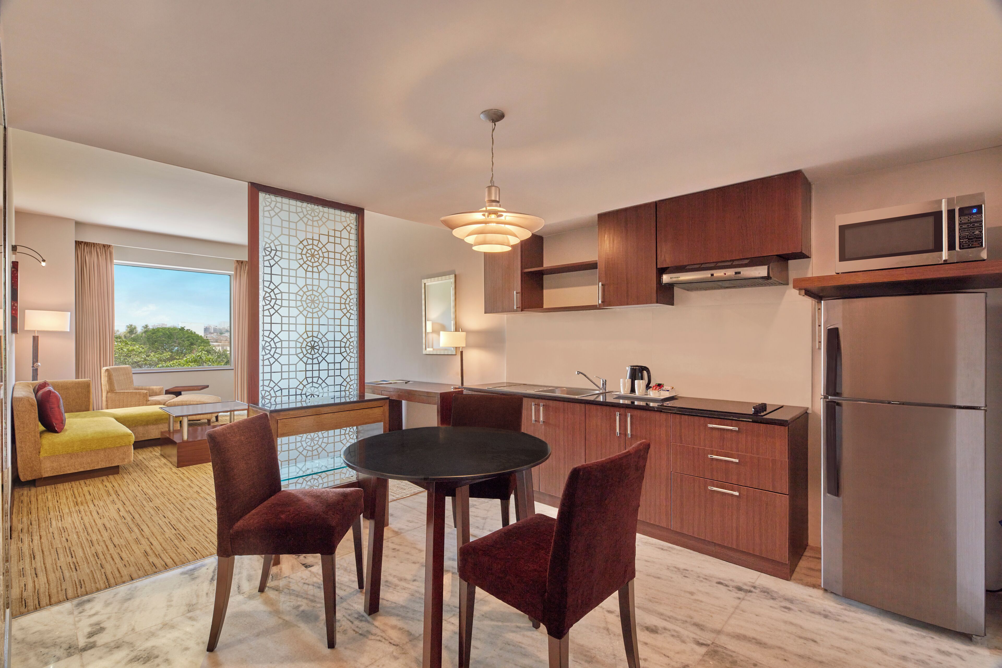 A modern kitchen with wooden cabinets, a stainless steel refrigerator, and a dining area with a round table and chairs.