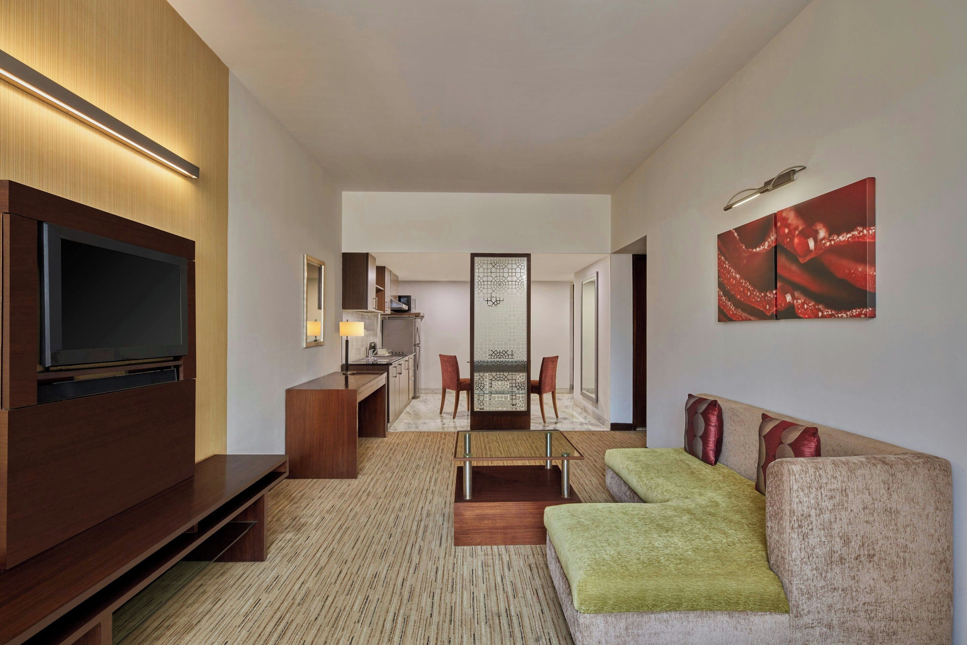 Une chambre d’hôtel moderne équipée d’une télévision à écran plat, d’un canapé, d’un coin repas et d’une cuisine.