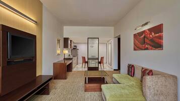 Una habitación de hotel moderna con televisión de pantalla plana, un sofá, un comedor y una cocina.