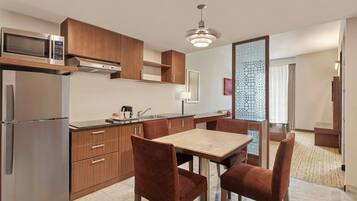 A modern kitchen with stainless steel appliances, wooden cabinets, and a dining area with a marble table and upholstered chairs.