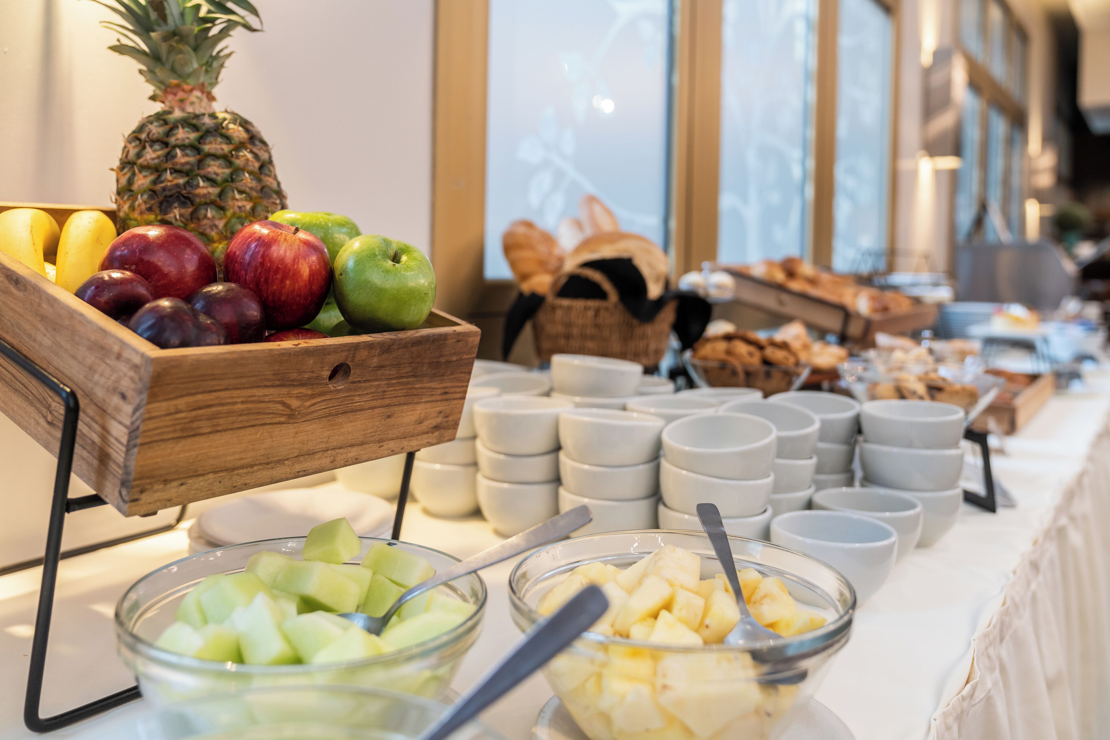 A buffet with various fruits, bowls, and plates arranged on a table.