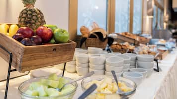 A buffet with various fruits, bowls, and plates arranged on a table.
