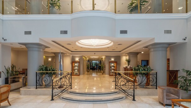 A spacious lobby with a central staircase, large columns, and potted plants. - Hotel Intersur Recoleta (Buenos Aires)