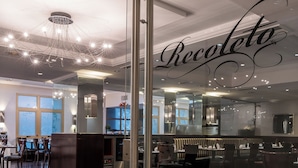 A modern restaurant interior with a glass partition, wooden flooring, and a chandelier. - Hotel Intersur Recoleta (Buenos Aires)