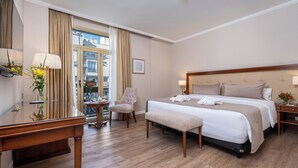 A hotel room with a large bed, a desk, a chair, and a small table with a vase of flowers. - Hotel Intersur Recoleta (Buenos Aires)