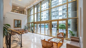 A spacious lobby with a staircase, seating area, and large windows offering views of the city. - Hotel Intersur Recoleta (Buenos Aires)