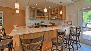 A bar area with wooden cabinets, a long counter, and bar stools. - Hilton Garden Inn Mount Laurel Philadelphia (Mount Laurel)