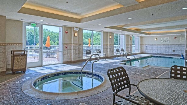 A pool area with a hot tub, lounge chairs, and a view of the outdoors. - Hilton Garden Inn Mount Laurel Philadelphia (Mount Laurel)