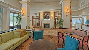 A spacious lobby with a fireplace, seating areas, and a reception desk. - Hilton Garden Inn Mount Laurel Philadelphia (Mount Laurel)