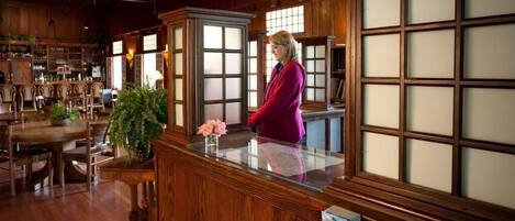 A bar area with wooden furniture, a reception desk, and a large window with frosted glass panels.