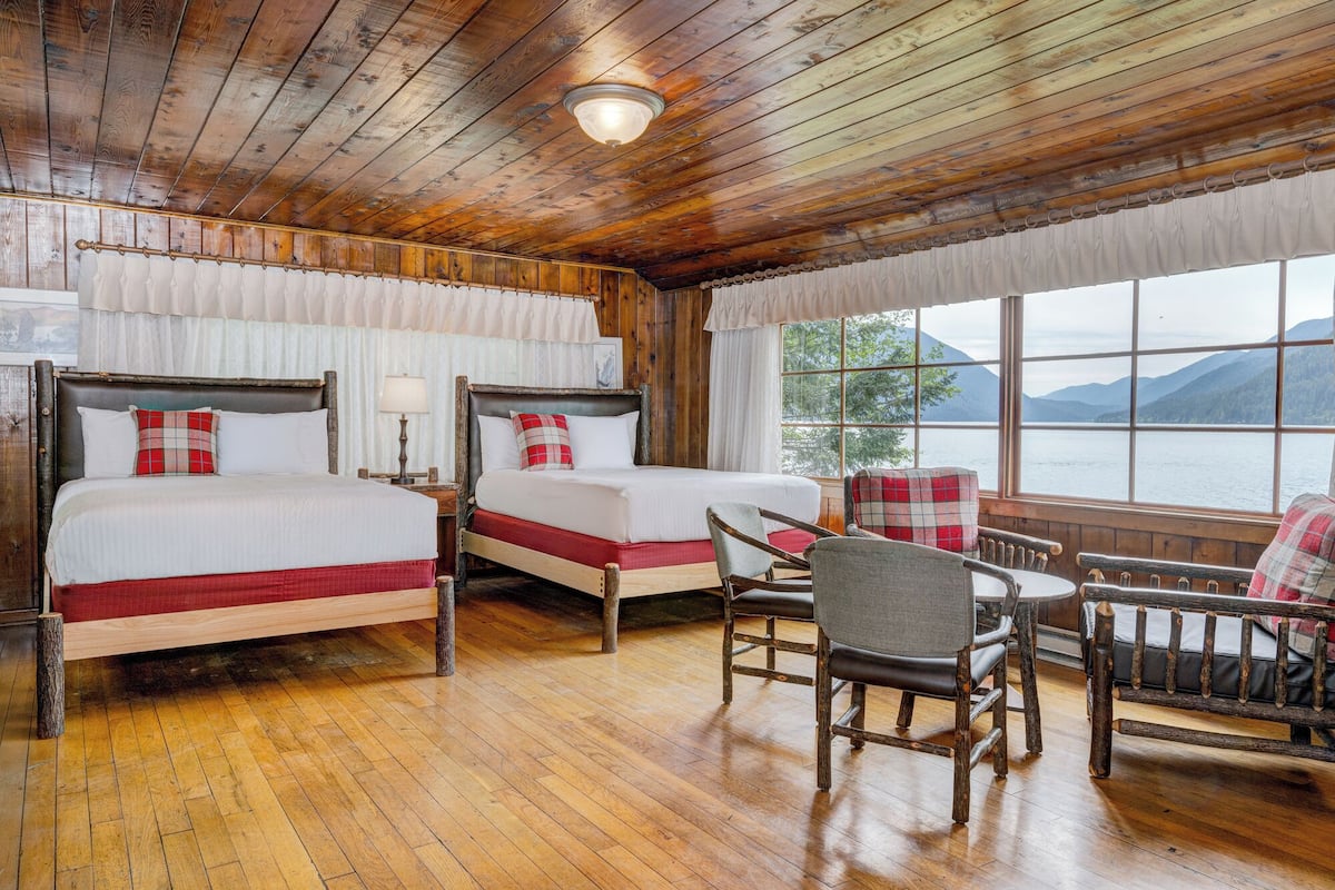 A wooden cabin room with two beds, a table, and chairs.