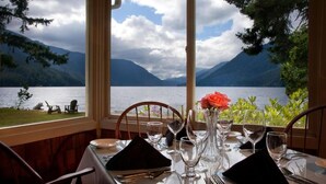 A dining table set for two with a view of a lake and mountains.