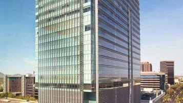 A high-rise hotel with a modern glass facade, multiple floors, and a rooftop pool area.