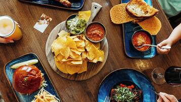 A dining table with various dishes including nachos, a burger, and a steak with vegetables.