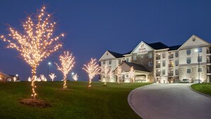 A multi-story hotel with a stone facade, multiple balconies, and a well-lit entrance. - Berlin Grande Hotel (Millersburg)