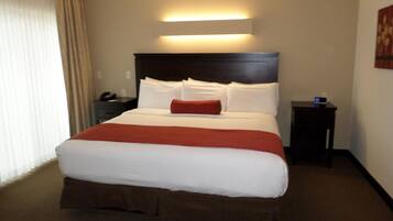 Habitación de hotel con una cama grande, una mesita de noche, una lámpara y una luz empotrada en la pared.