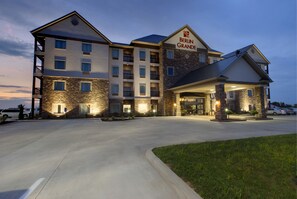 Ein mehrstöckiges Hotel mit Steinfassade, mehreren Balkonen und einem gut beleuchteten Eingang.