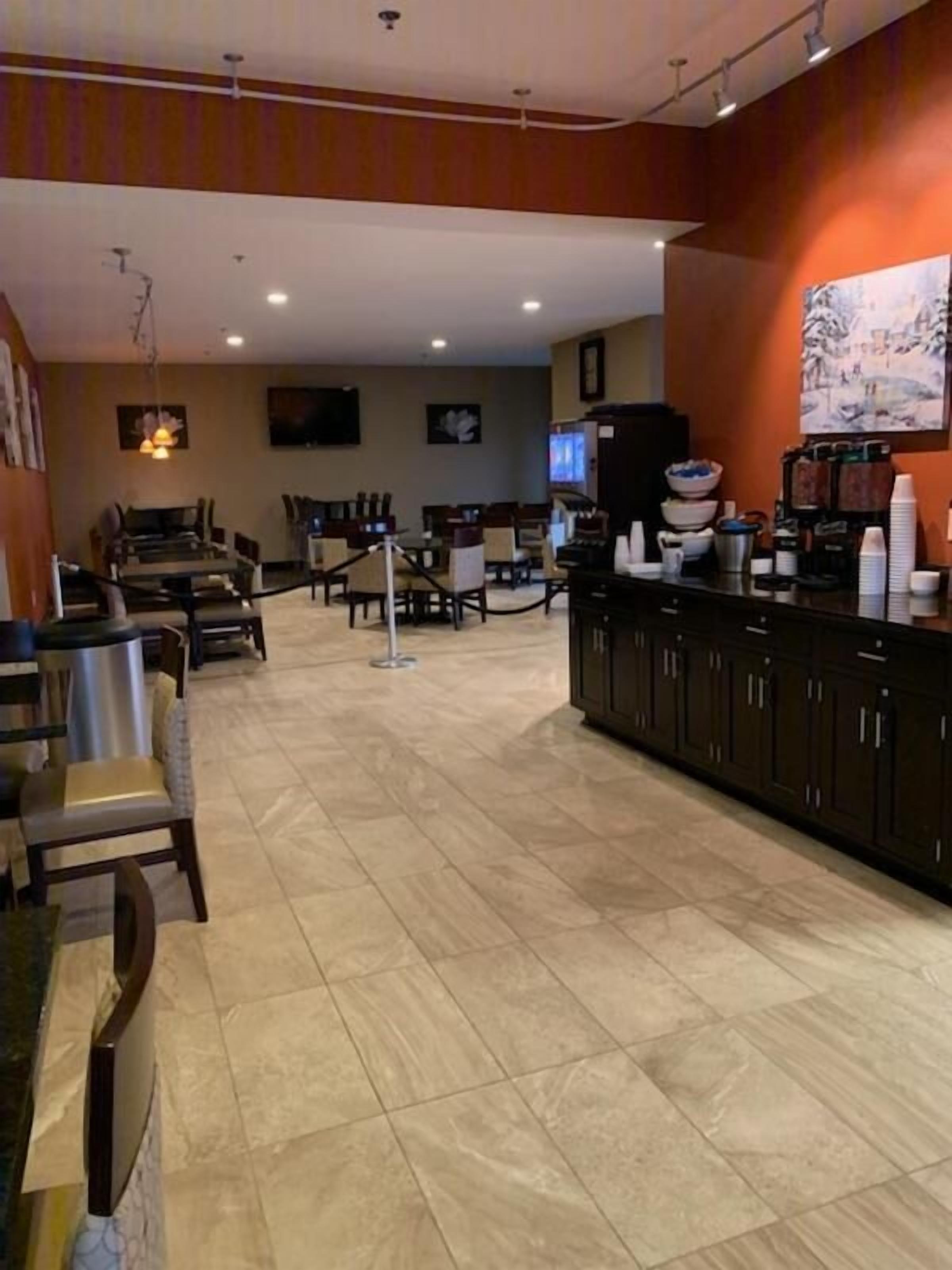 Een ruime hotellobby met een centrale zithoek, een receptiebalie en een koffieautomaat.