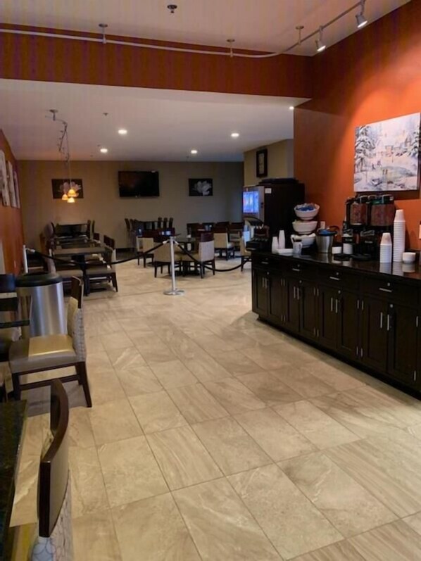 Un amplio vestíbulo de hotel con una zona de estar central, una recepción y una estación de café.