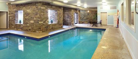 An indoor swimming pool with a stone wall, a small window, and a door.