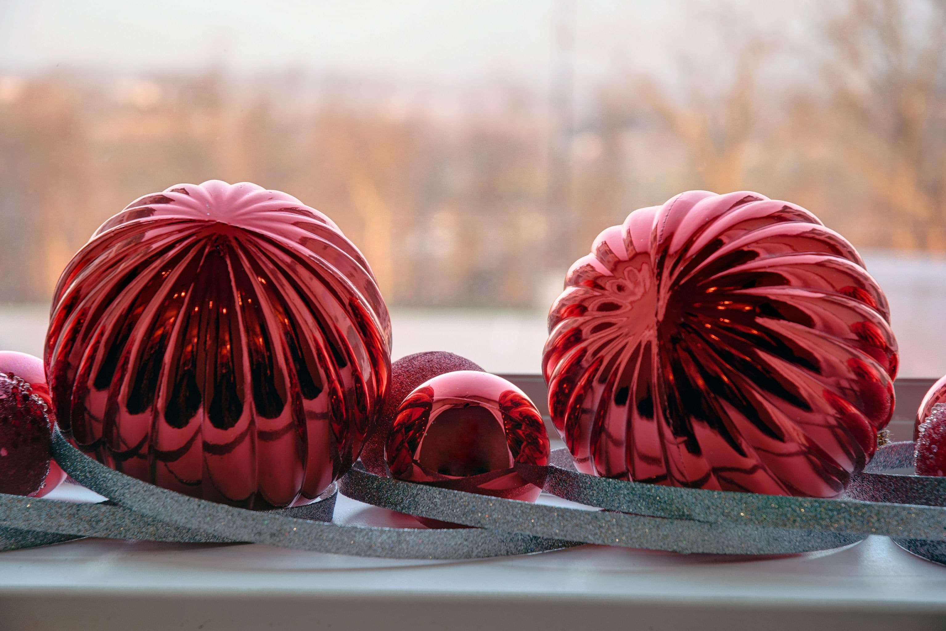 A close-up of red Christmas ornaments with a glittery ribbon.