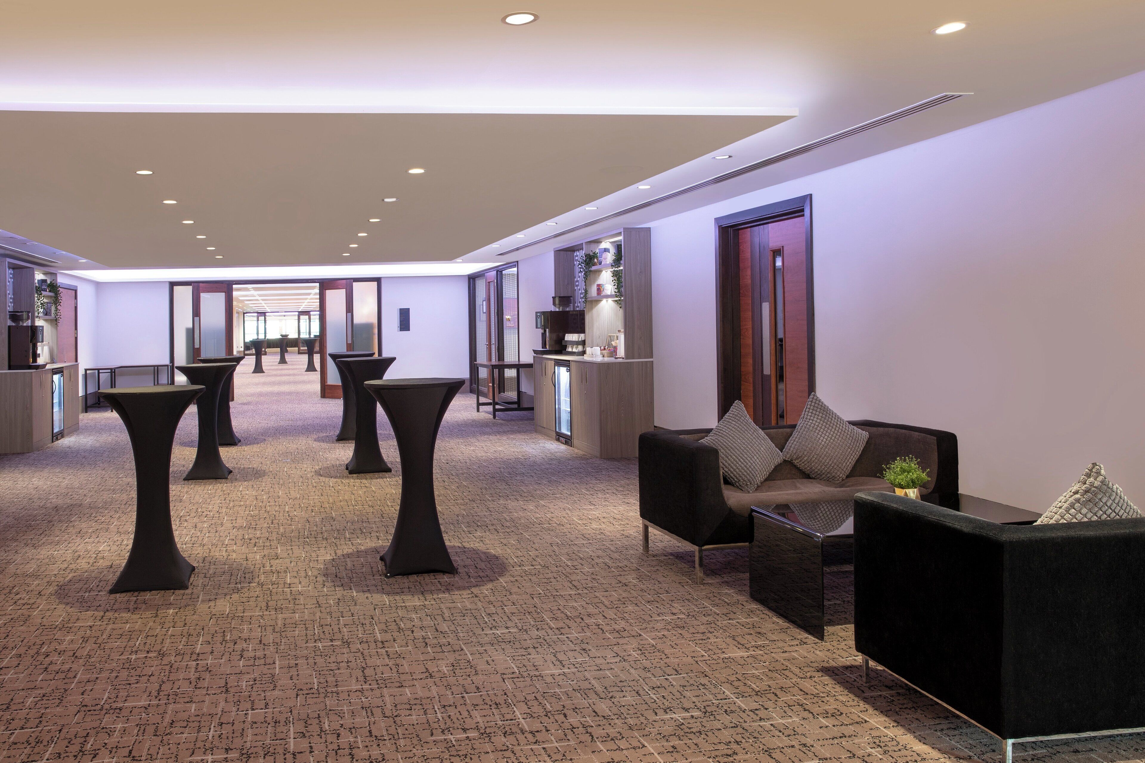 A modern lobby with a reception desk, seating area, and a view of the hallway.