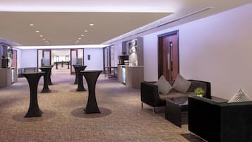 A modern lobby with a reception desk, seating area, and a view of the hallway.