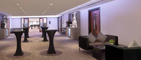 A modern lobby with a reception desk, seating area, and a view of the hallway.