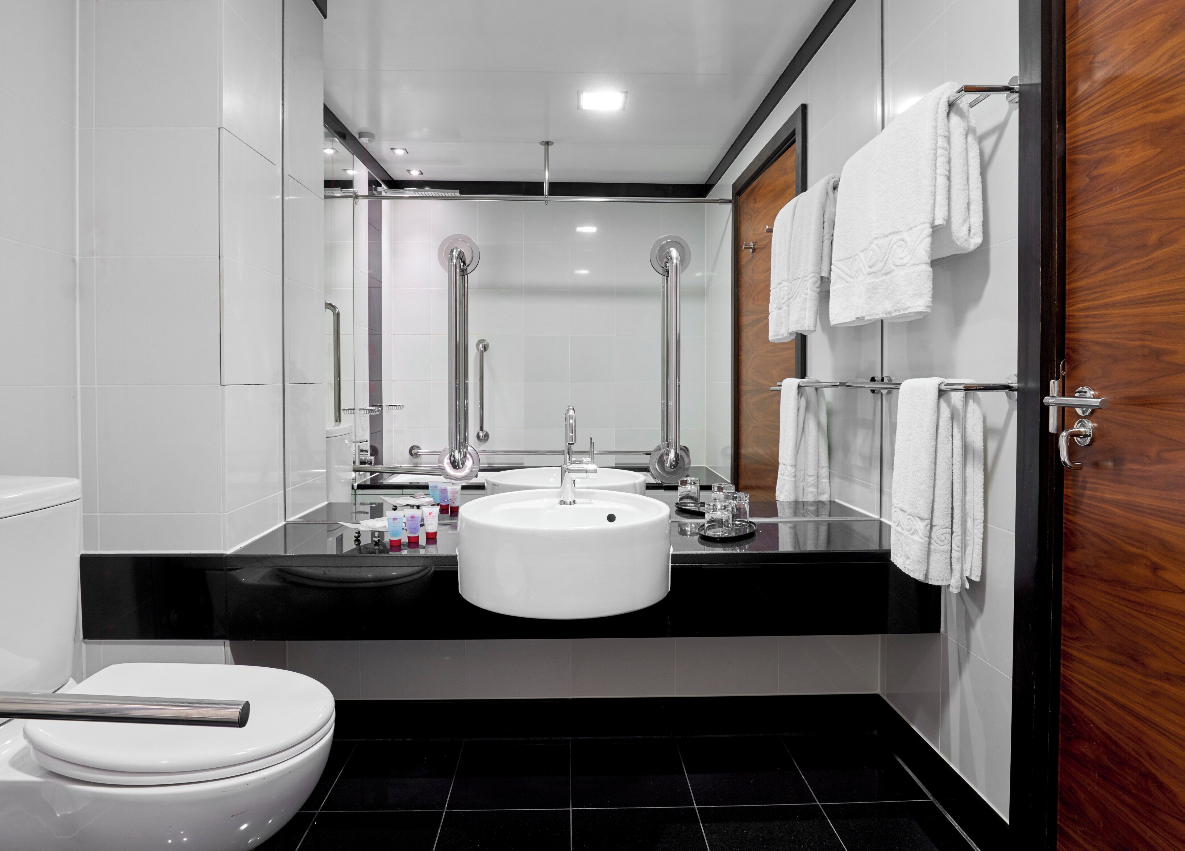 A modern bathroom with a white sink, a toilet, and a shower area.