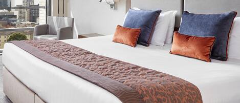 Een hotelkamer met een groot bed, stadszicht, een moderne lamp en een stoel.