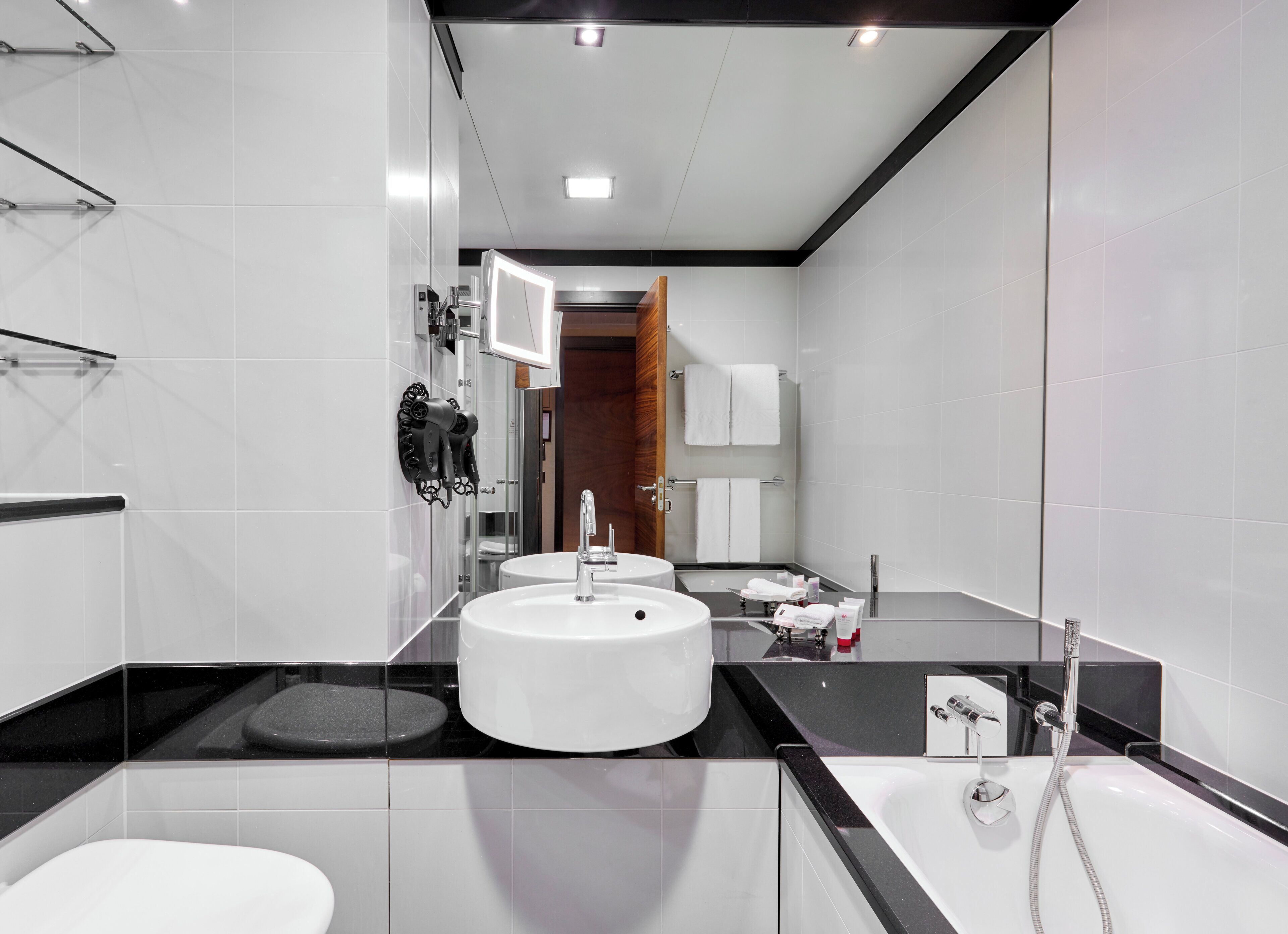 Une salle de bain moderne avec un grand miroir, deux lavabos, une baignoire et une cabine de douche en verre.
