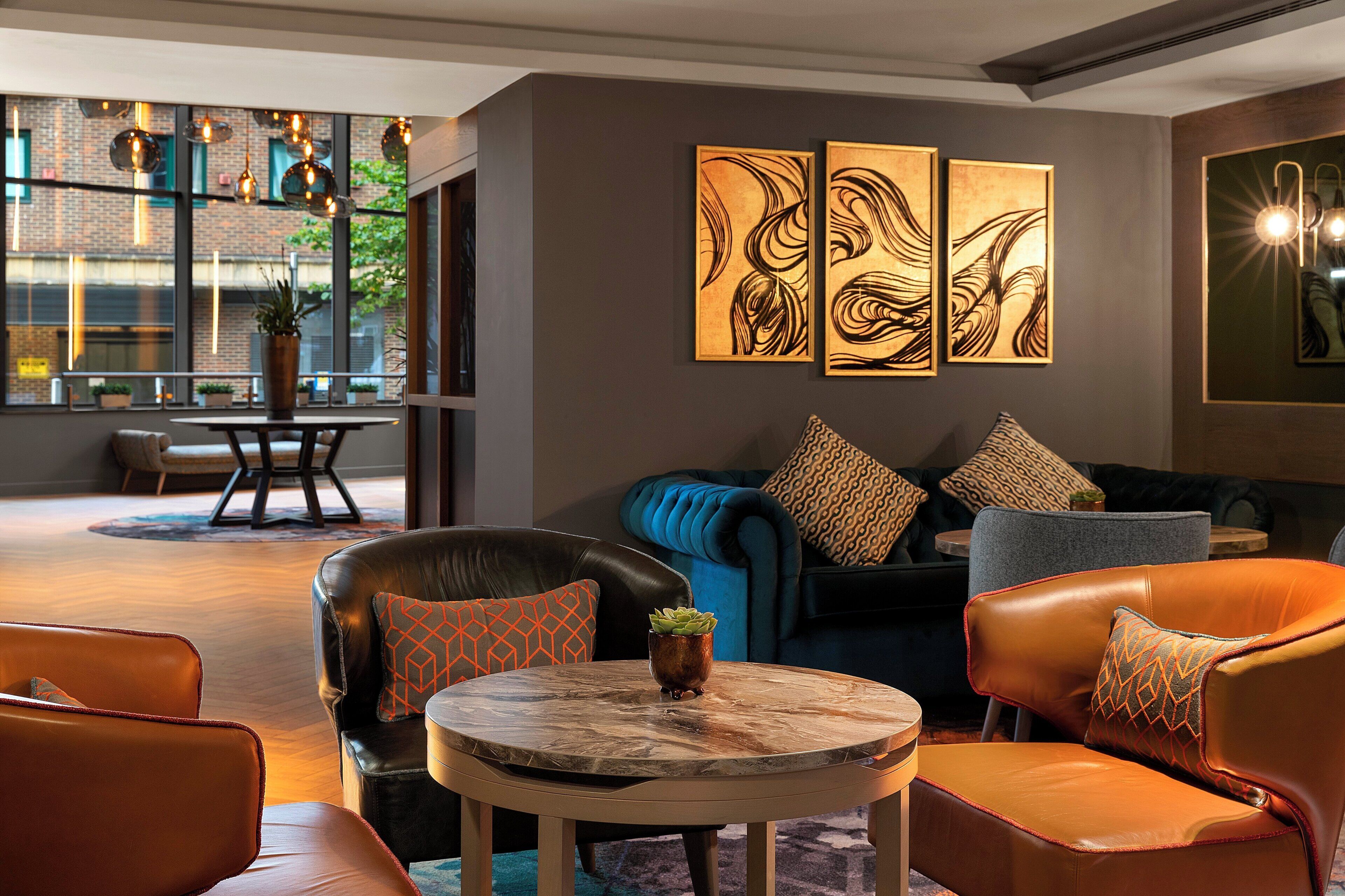 Un'area lounge moderna con divani in pelle, un tavolino rotondo e opere d'arte astratte alle pareti.