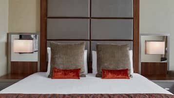 A hotel room with a large bed, two pillows, a patterned blanket, and bedside lamps.