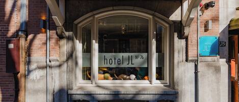 Een hotelentree met een groot rondboogvenster dat diverse objecten binnen toont.