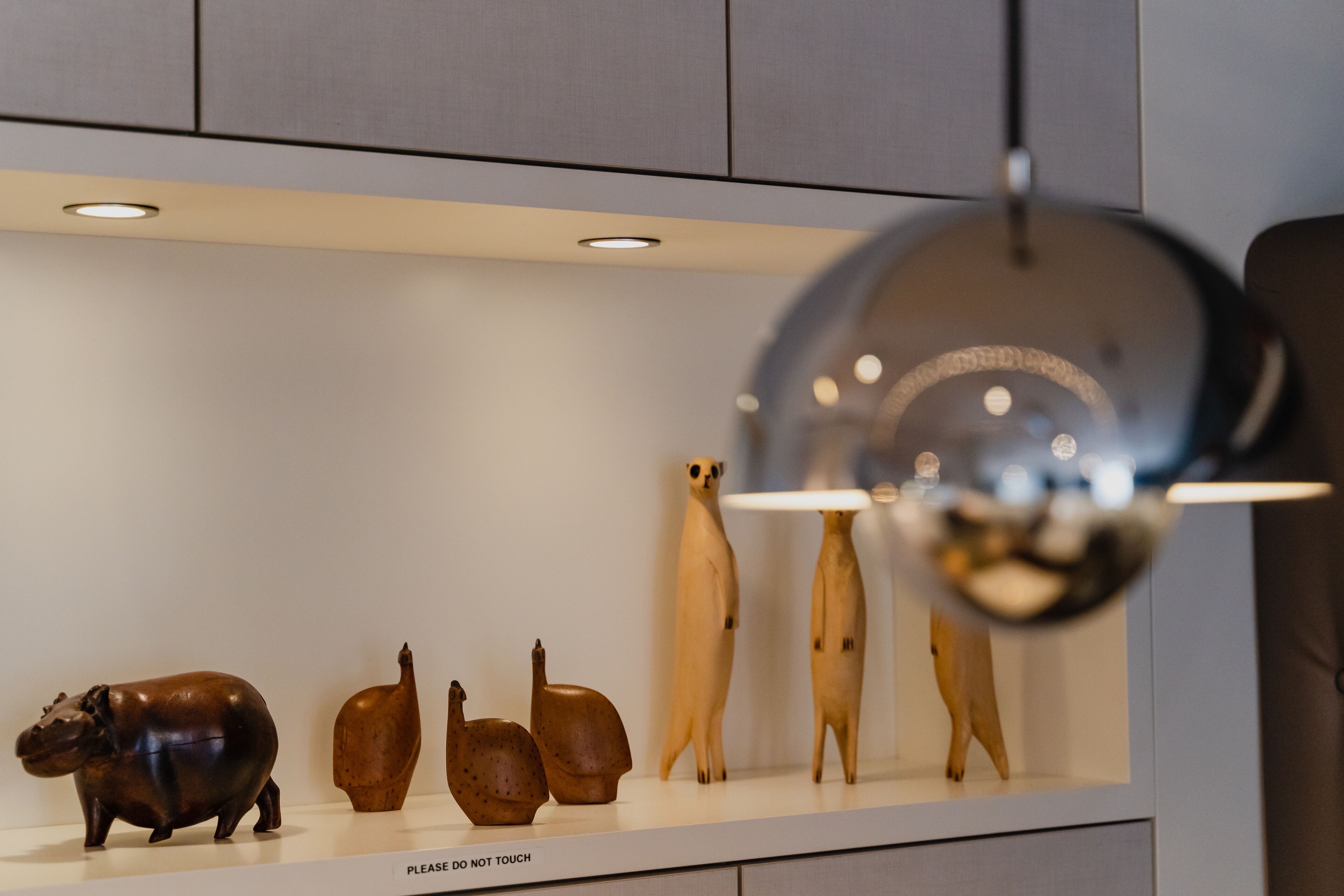 A display of animal figurines on a shelf with a 'Please do not touch' sign.