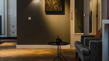 A modern living room with a dark wall, a round table with a black base, and a gray sofa.