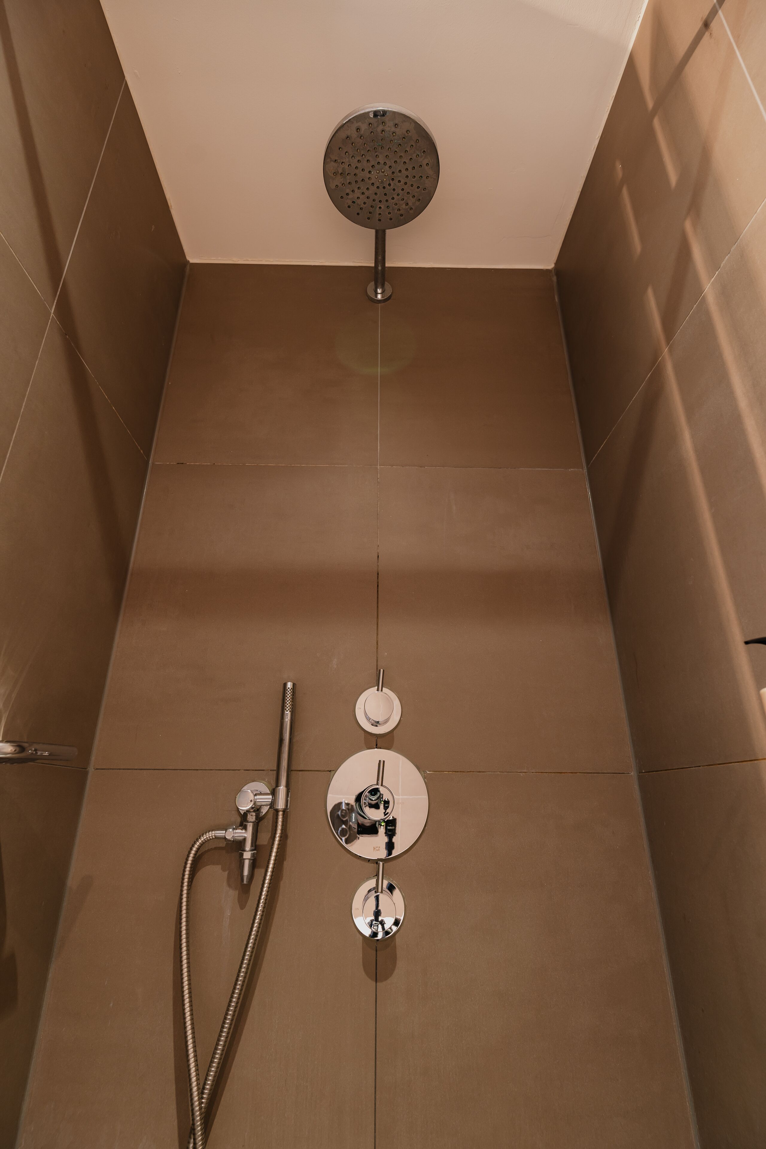 A modern shower with a handheld showerhead and a wall-mounted faucet.