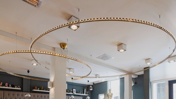 A modern lounge area with a patterned carpet, comfortable seating, and a decorative ceiling light fixture. - Hotel JL No76 (Amsterdam)