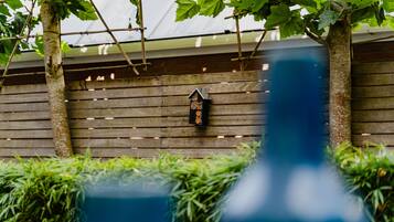 Una pared de madera con un comedero para pájaros y plantas verdes.