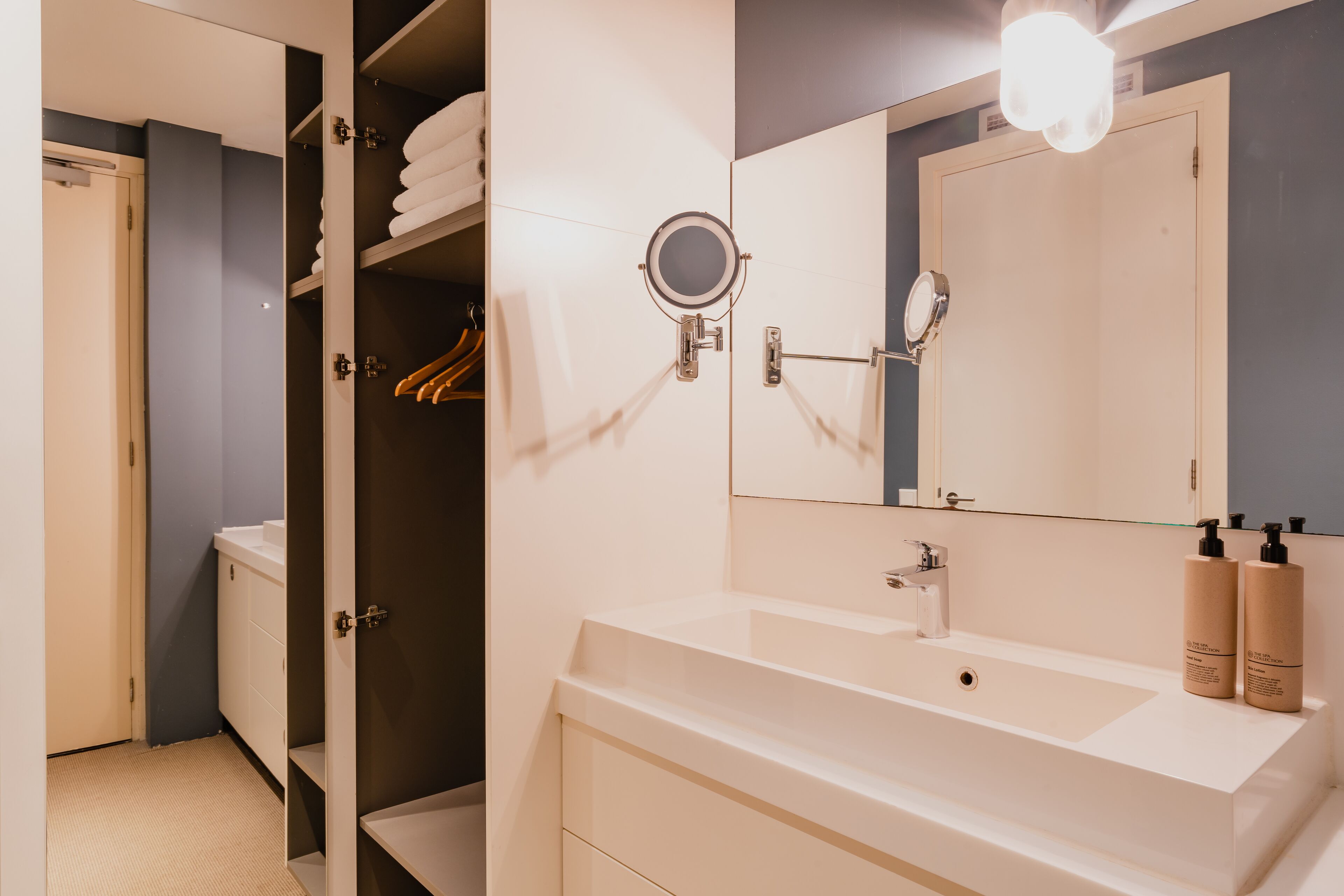 A modern bathroom with a large mirror, a sink, and a shower area.