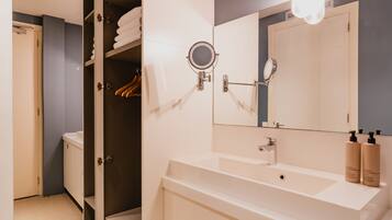 A modern bathroom with a large mirror, a sink, and a shower area.