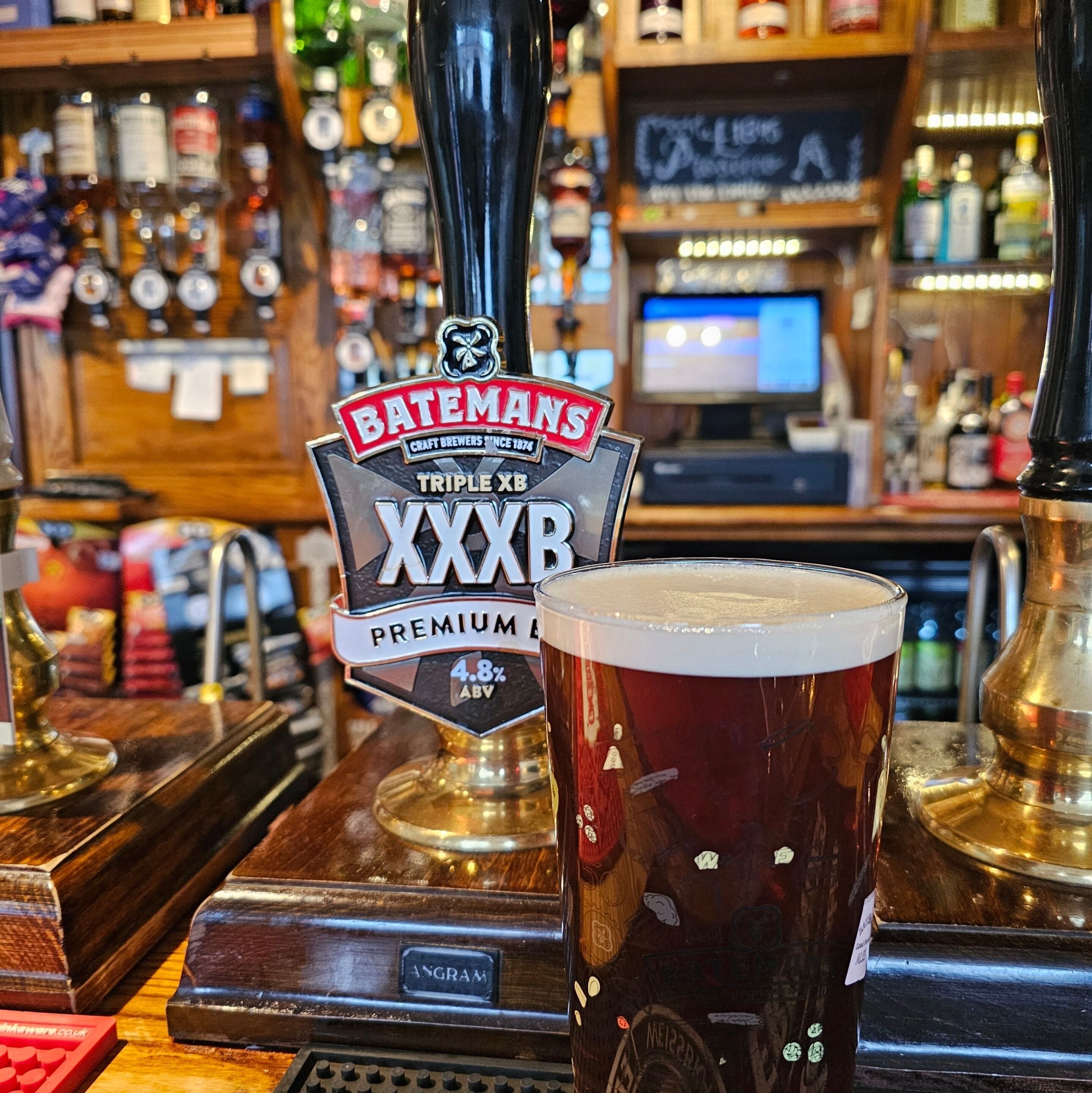 A bar with a beer tap labeled "Bateman's Triple XB Premium Lager" and a glass of beer.