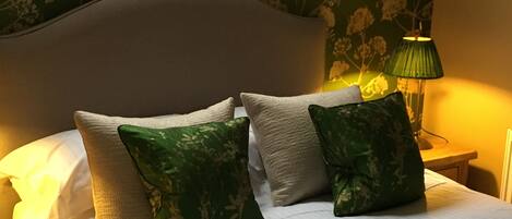 A neatly made bed with white bedding and two green patterned pillows.