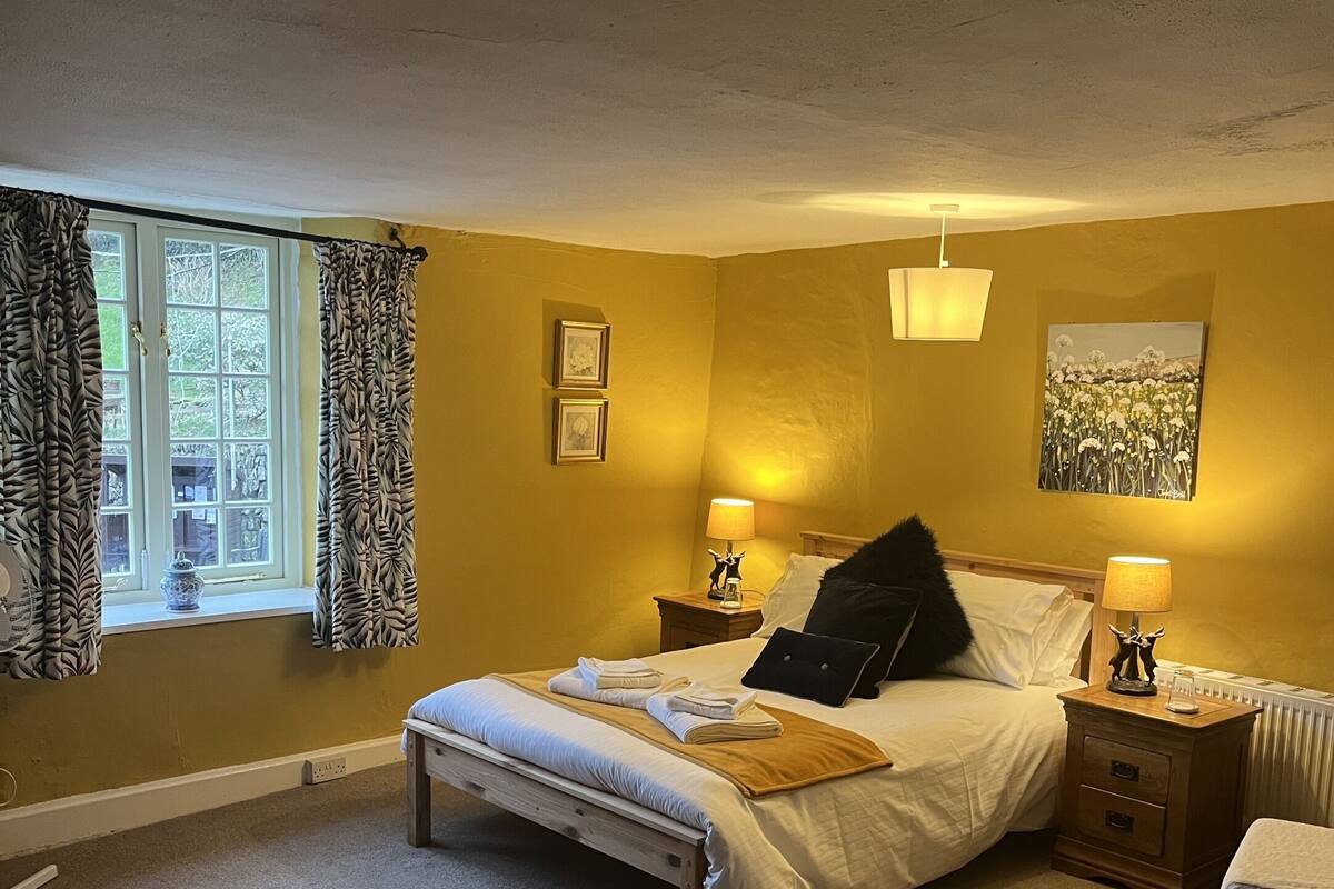 A bedroom with a bed, bedside tables, a lamp, a chair, and a window with curtains.